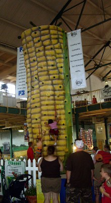 [Climbing wall painted to resemble an ear of corn. Two young climbers are scaling it.]